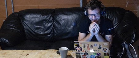 A person wearing headphones and sitting at a table with a computer and a cup of coffee

Description automatically generated with low confidence